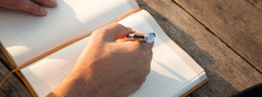 man-writing-in-notebook